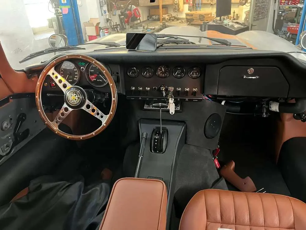Cockpit mit Holzlenkrad, Instrumenten im Stil der Zeit und sattelbraunem Leder